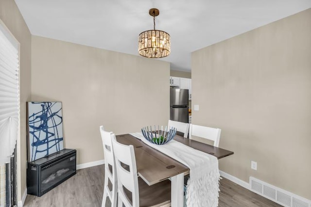 dining room featuring light wood-style floors, visible vents, baseboards, and a notable chandelier