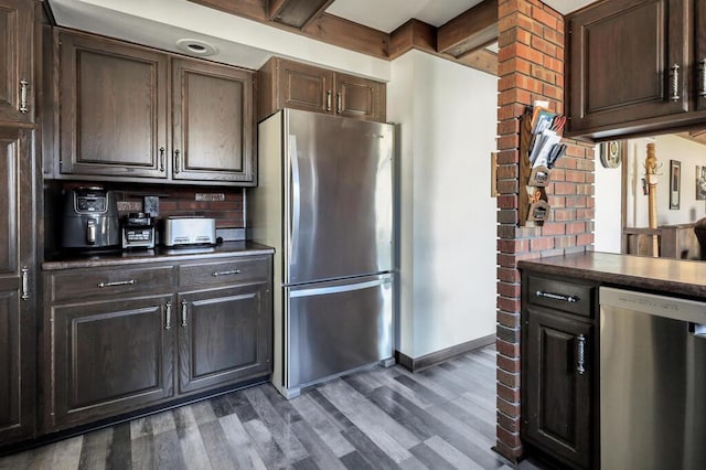 kitchen featuring dark wood-style floors, baseboards, dark brown cabinets, appliances with stainless steel finishes, and dark countertops