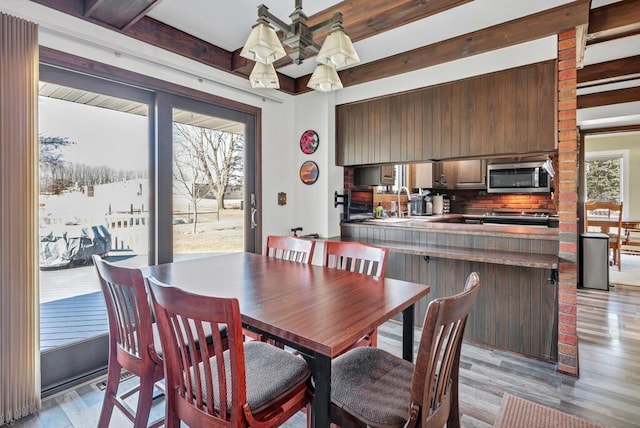 dining room with light wood finished floors and beamed ceiling