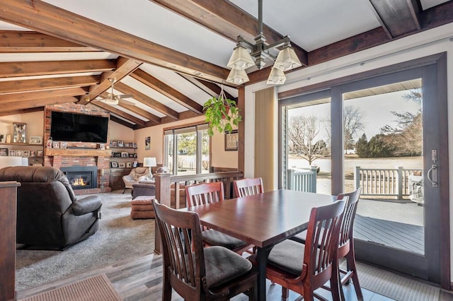 dining room with vaulted ceiling with beams, a fireplace, and ceiling fan