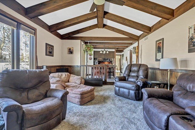 living room with visible vents, a wainscoted wall, carpet floors, lofted ceiling with beams, and ceiling fan with notable chandelier