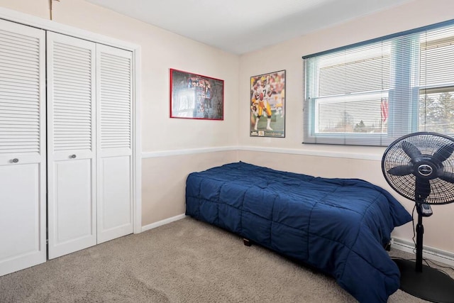 carpeted bedroom with a closet and baseboards