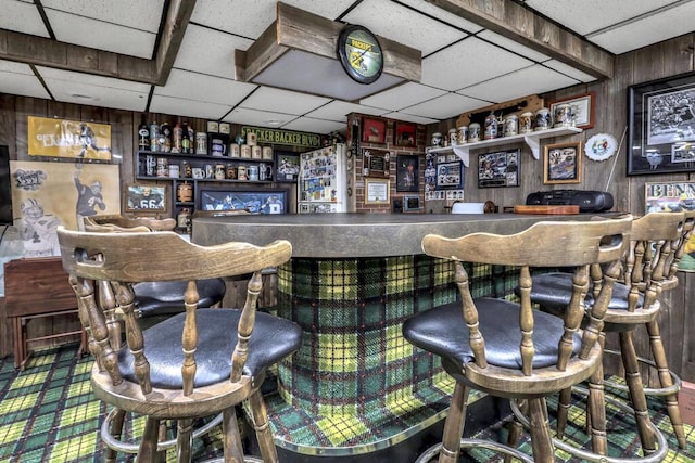 bar with a drop ceiling, bar, and wooden walls