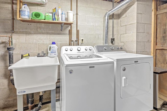 washroom with a sink, laundry area, concrete block wall, and separate washer and dryer