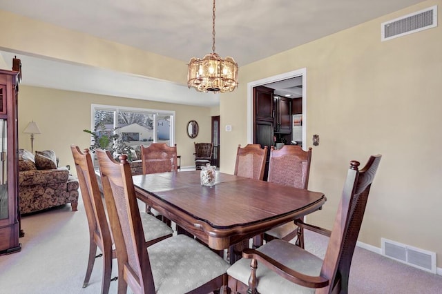 dining room with a notable chandelier, visible vents, light colored carpet, and baseboards