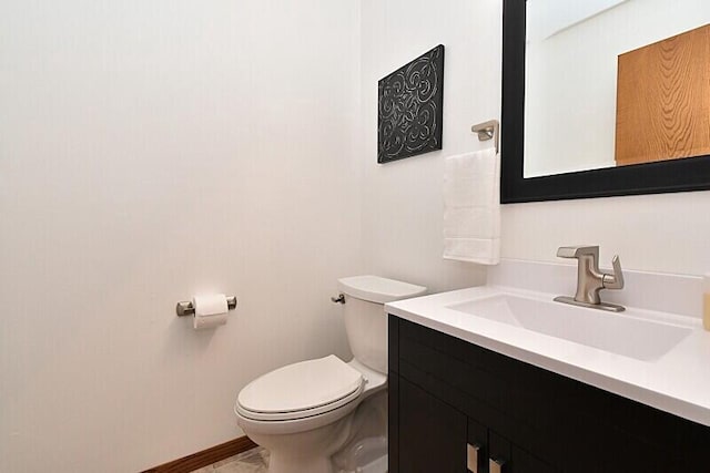 bathroom featuring toilet, vanity, and baseboards