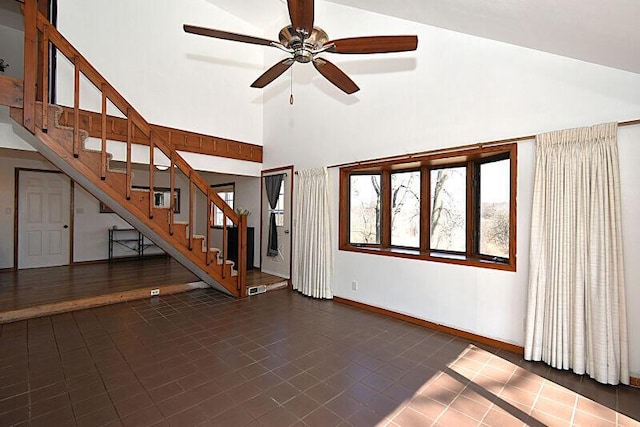 interior space featuring stairs, ceiling fan, baseboards, and high vaulted ceiling