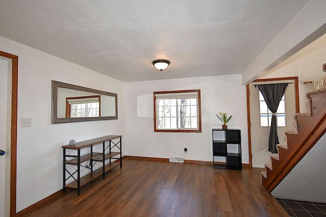 entrance foyer featuring dark wood-style floors, visible vents, stairs, and baseboards