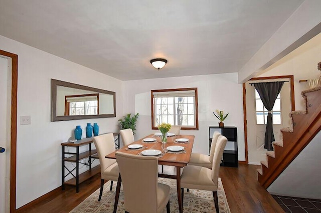 dining space with a wealth of natural light, stairs, baseboards, and dark wood-style flooring