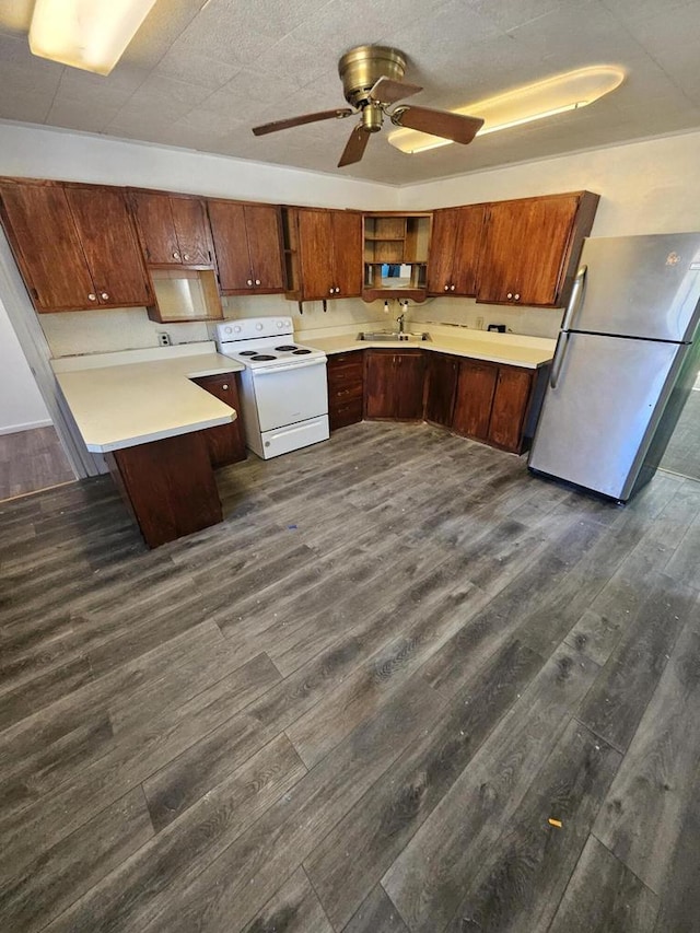 kitchen featuring white electric range, dark wood finished floors, freestanding refrigerator, a ceiling fan, and a sink