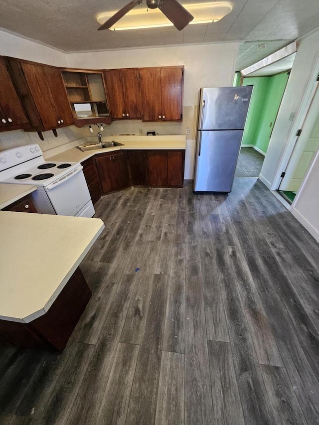 kitchen with white electric range, a sink, dark wood-style floors, freestanding refrigerator, and light countertops