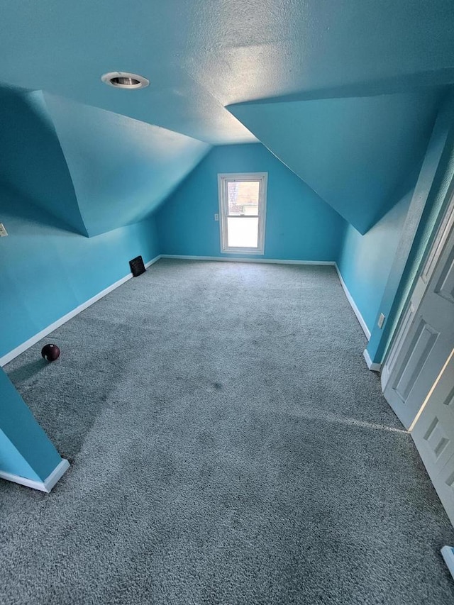 bonus room with lofted ceiling, carpet flooring, baseboards, and a textured ceiling