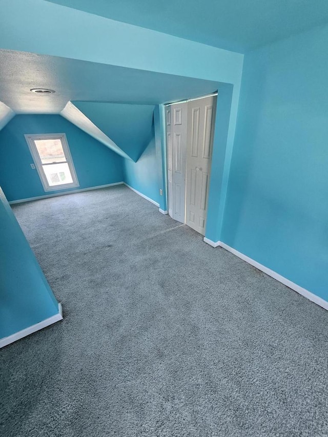 bonus room featuring baseboards, carpet flooring, a textured ceiling, and lofted ceiling