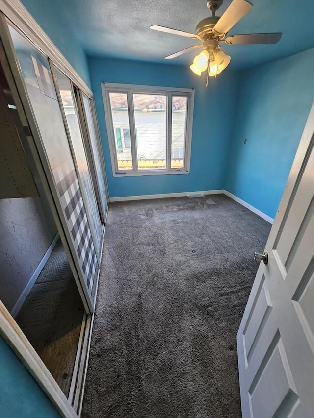 empty room featuring ceiling fan, carpet, baseboards, and a textured ceiling