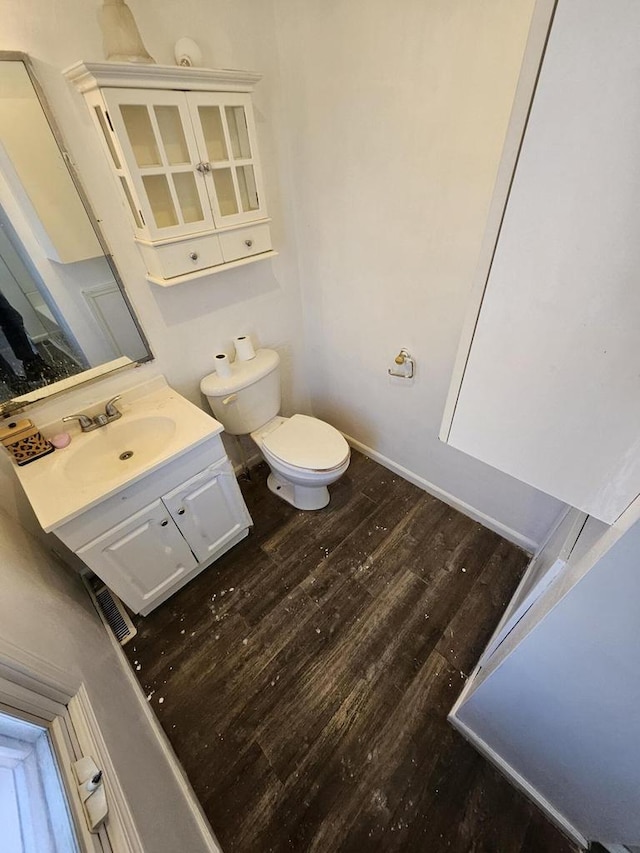 bathroom with toilet, vanity, and wood finished floors