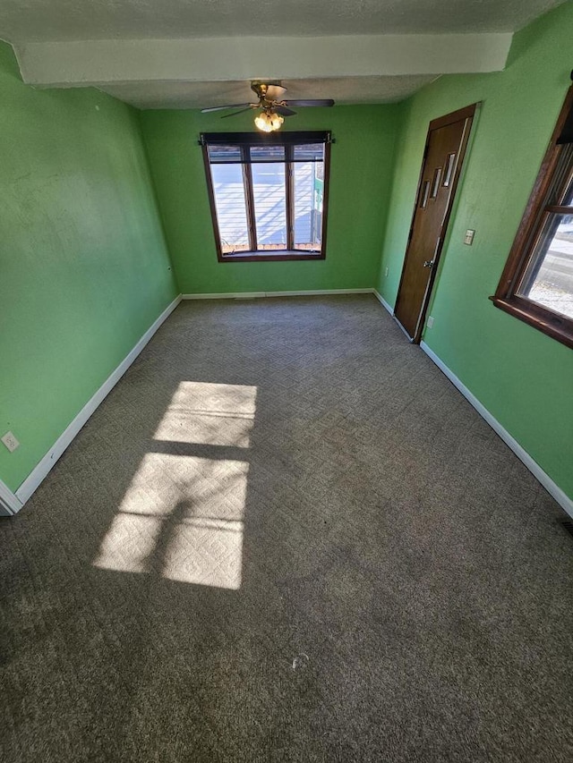 carpeted spare room with a ceiling fan and baseboards