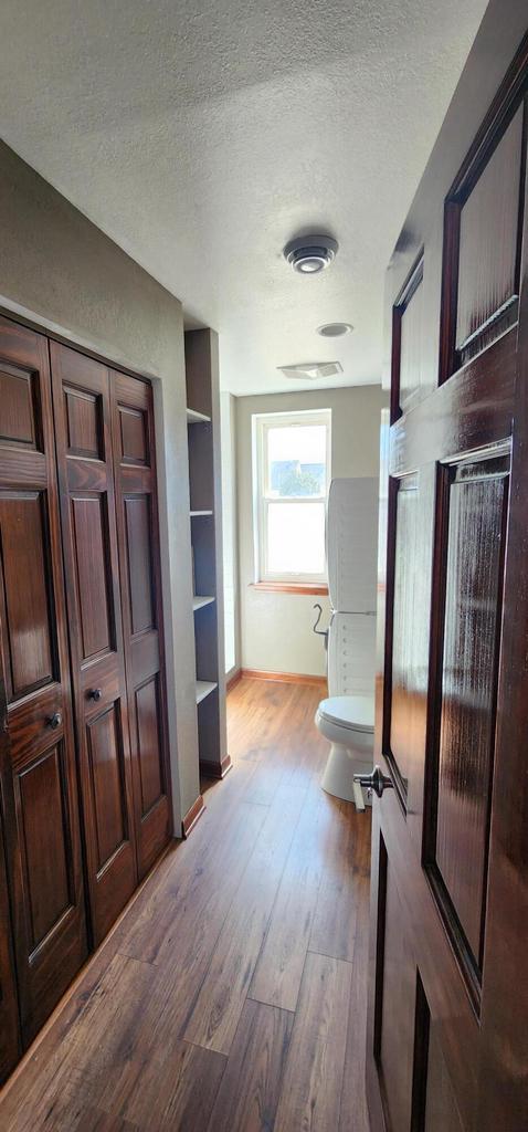 bathroom featuring toilet, wood finished floors, built in shelves, and a textured ceiling