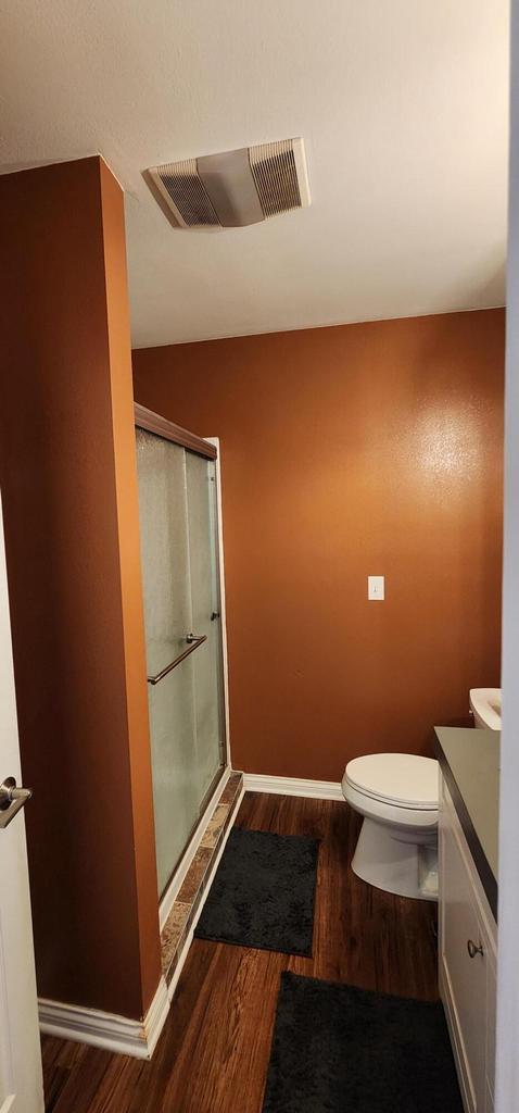 bathroom featuring vanity, wood finished floors, visible vents, and a stall shower