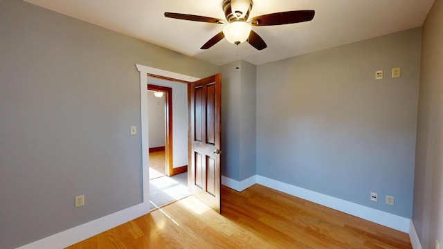 empty room featuring baseboards, a ceiling fan, and light wood finished floors