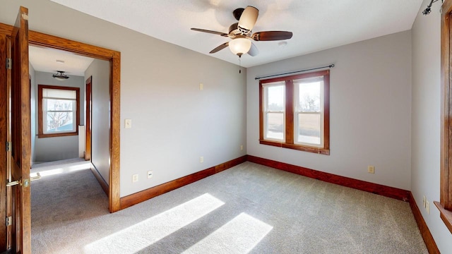 unfurnished room featuring a wealth of natural light, carpet flooring, and baseboards