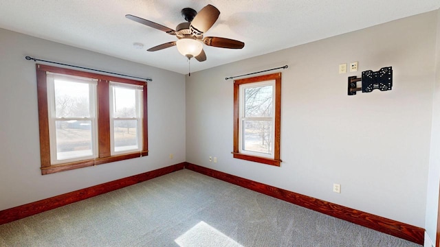 carpeted empty room with a textured ceiling, a healthy amount of sunlight, baseboards, and ceiling fan