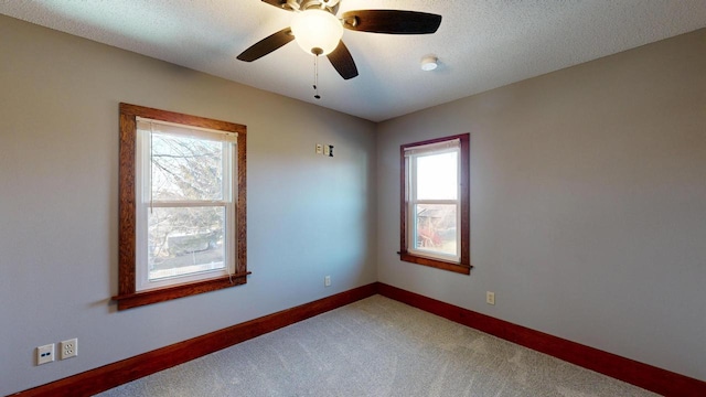 spare room with baseboards, light colored carpet, ceiling fan, and a textured ceiling