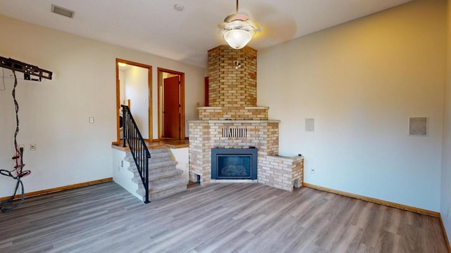 unfurnished living room featuring visible vents, stairs, baseboards, and wood finished floors