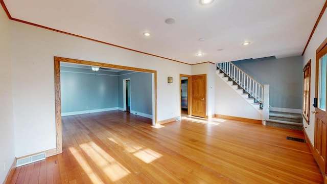 unfurnished living room with stairway, light wood-style flooring, visible vents, and baseboards