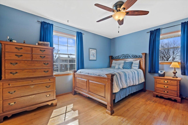 bedroom featuring multiple windows, light wood-style flooring, baseboards, and ceiling fan