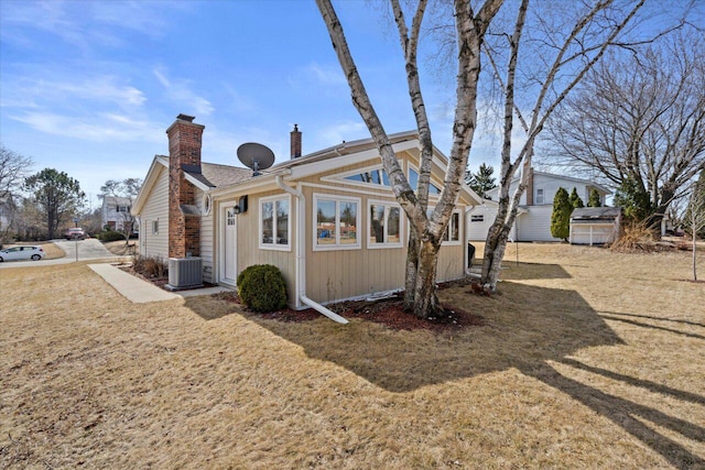 rear view of property with central AC unit and a chimney