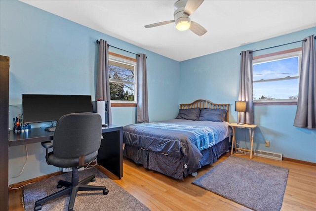 bedroom featuring visible vents, baseboards, wood finished floors, and a ceiling fan