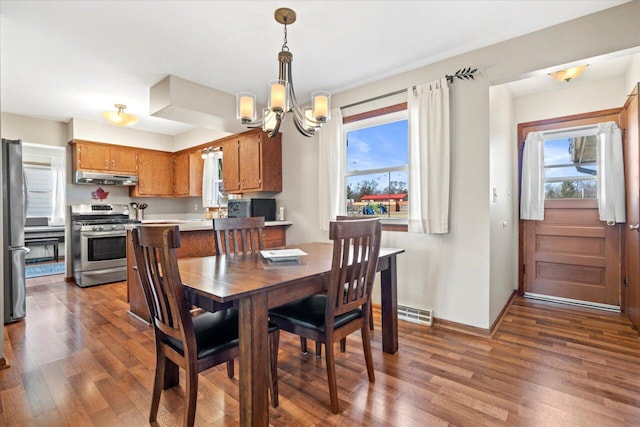 dining area featuring visible vents, baseboards, a notable chandelier, and wood finished floors