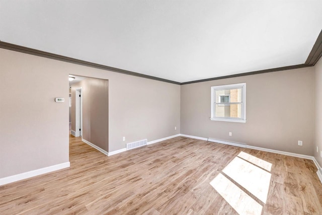 unfurnished room featuring light wood-type flooring, visible vents, baseboards, and ornamental molding