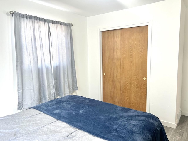 bedroom featuring a closet, baseboards, and wood finished floors