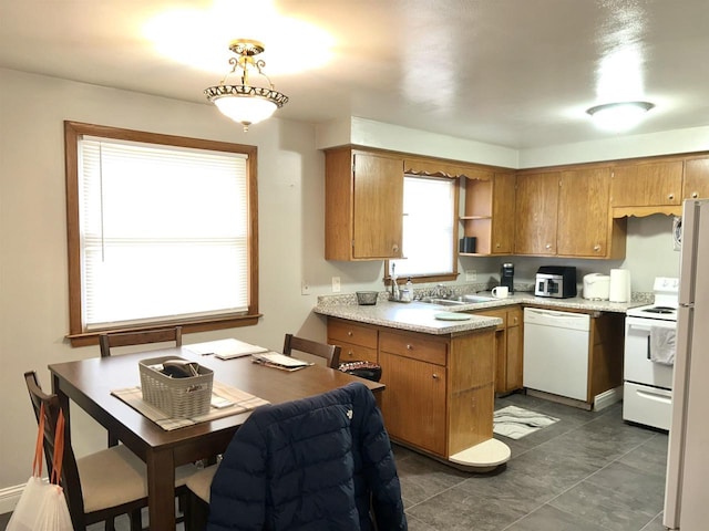 kitchen featuring brown cabinets, white appliances, and a peninsula