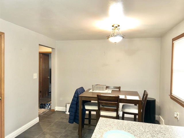 dining area with baseboards and dark tile patterned flooring