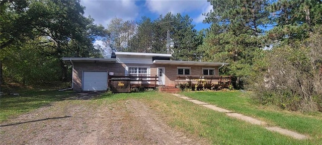 rear view of house featuring a wooden deck, an attached garage, dirt driveway, and a lawn