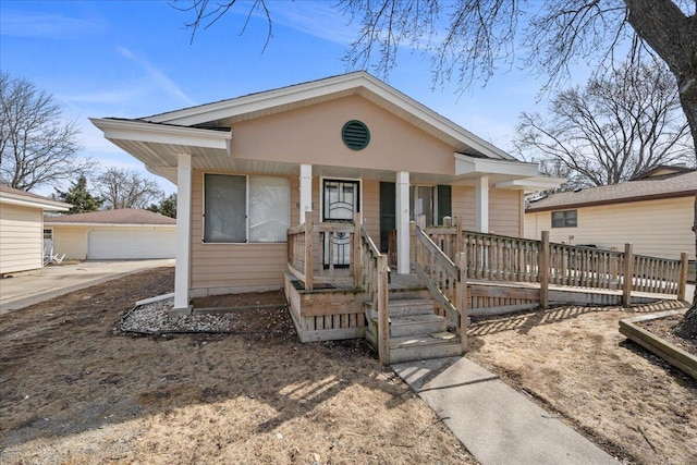 bungalow-style house with covered porch, a detached garage, and an outdoor structure