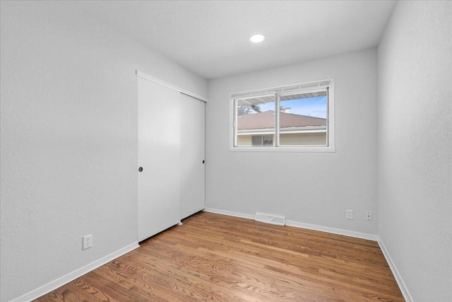 unfurnished room with visible vents, light wood-type flooring, and baseboards