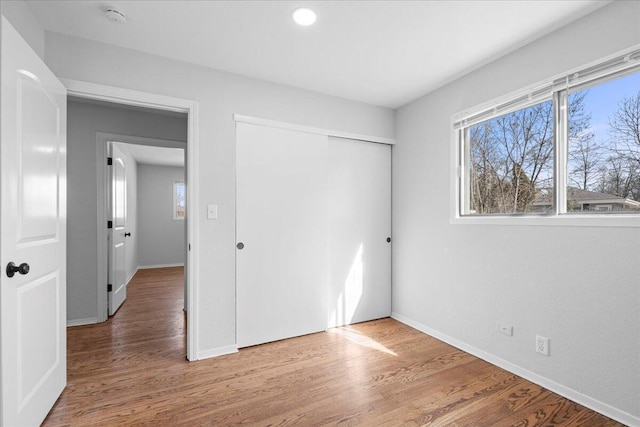 unfurnished bedroom featuring a closet, multiple windows, and wood finished floors