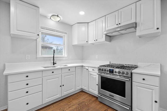 kitchen featuring under cabinet range hood, a sink, dark wood-style floors, stainless steel range with gas cooktop, and white cabinets