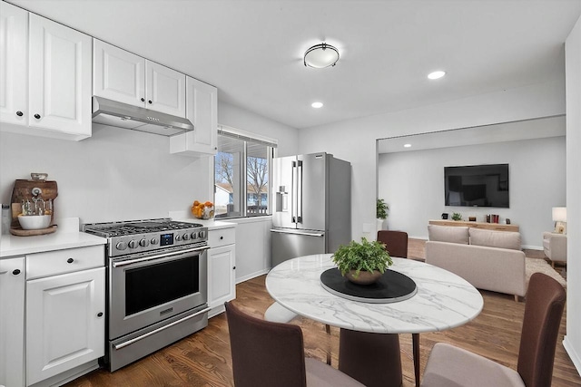 kitchen with dark wood finished floors, white cabinetry, under cabinet range hood, and stainless steel appliances