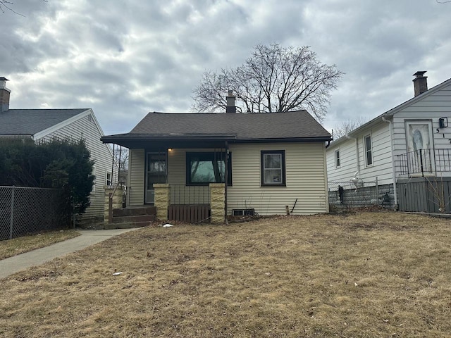 bungalow-style house with a front yard, fence, a porch, a chimney, and a shingled roof