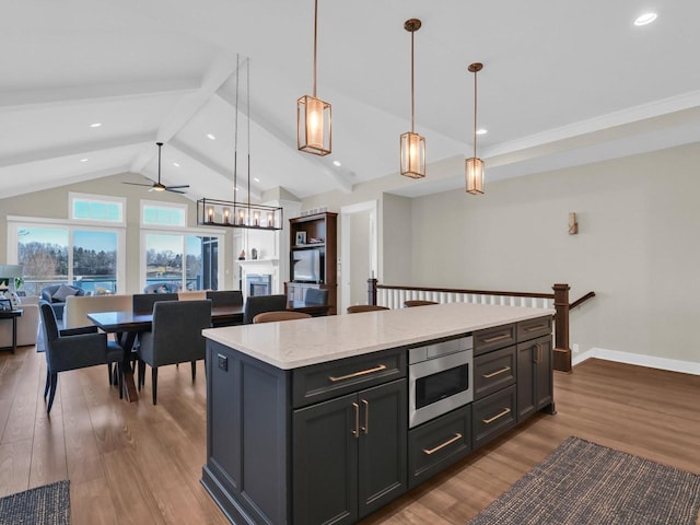 kitchen with stainless steel microwave, a center island, open floor plan, and light wood-type flooring