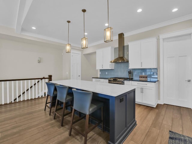 kitchen with a breakfast bar area, wood finished floors, decorative backsplash, stainless steel stove, and wall chimney range hood