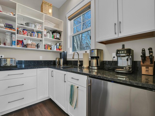 kitchen with dark stone counters, dark wood-style floors, refrigerator, white cabinetry, and a sink