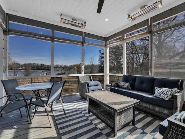 sunroom featuring ceiling fan and a water view