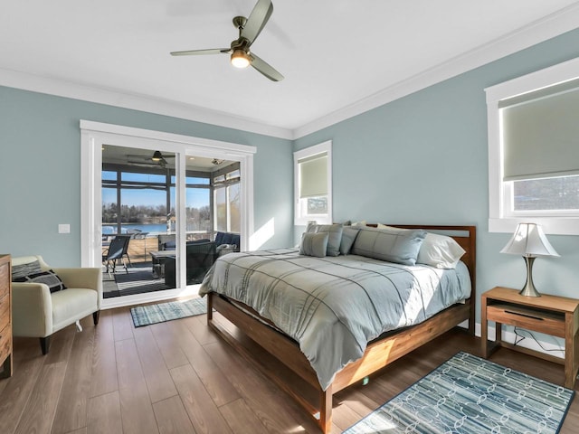 bedroom with ornamental molding, wood finished floors, a water view, and access to outside