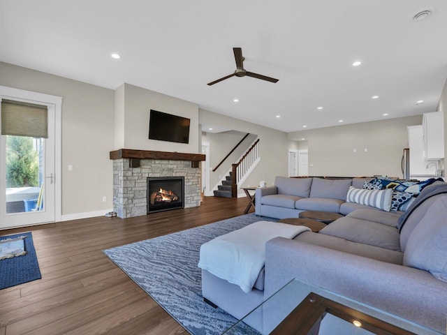 living area with wood finished floors, recessed lighting, a stone fireplace, baseboards, and ceiling fan