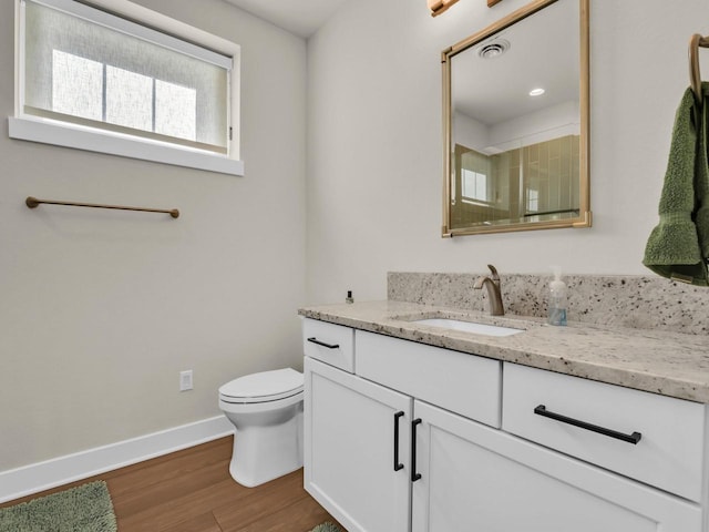 full bath featuring vanity, wood finished floors, baseboards, visible vents, and tiled shower